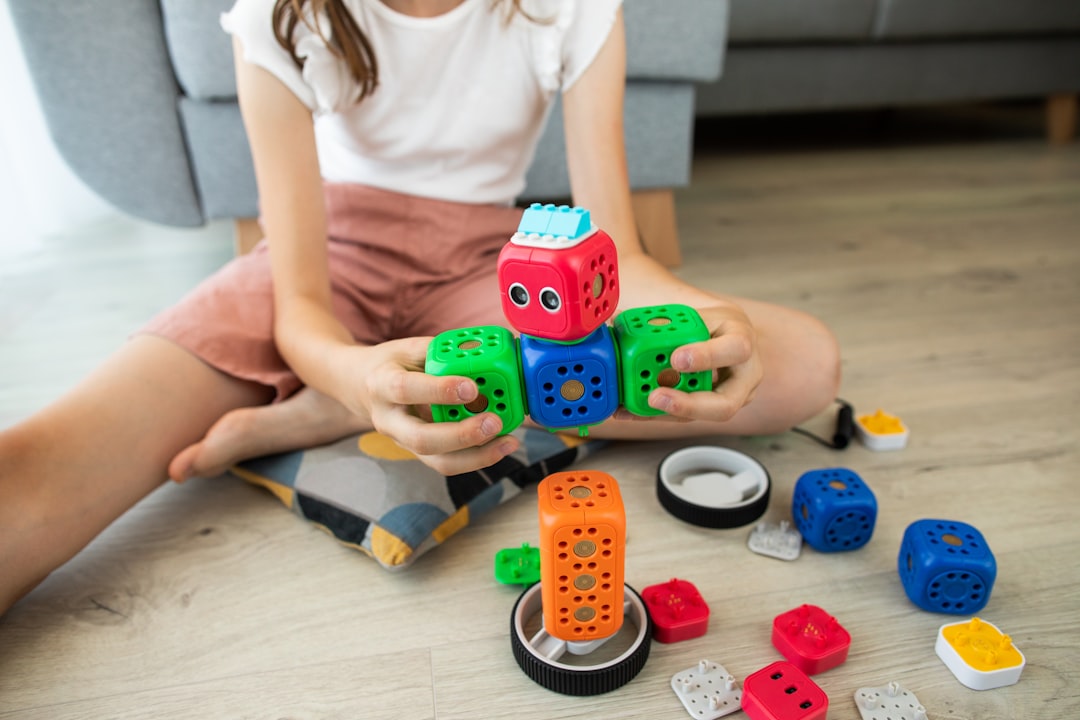 Girl building a toy robot by Robotic Coding girl in white shirt playing with blue and red car toy