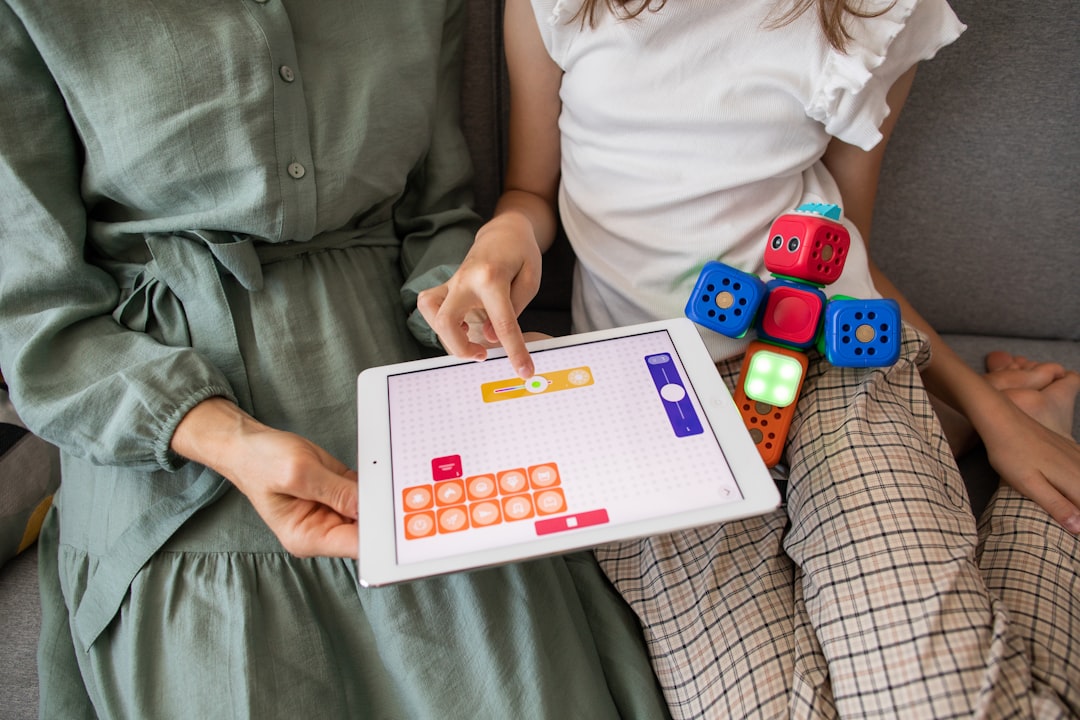 Mom and daughter learning visual programming by Robotic Coding child playing game on white ipad