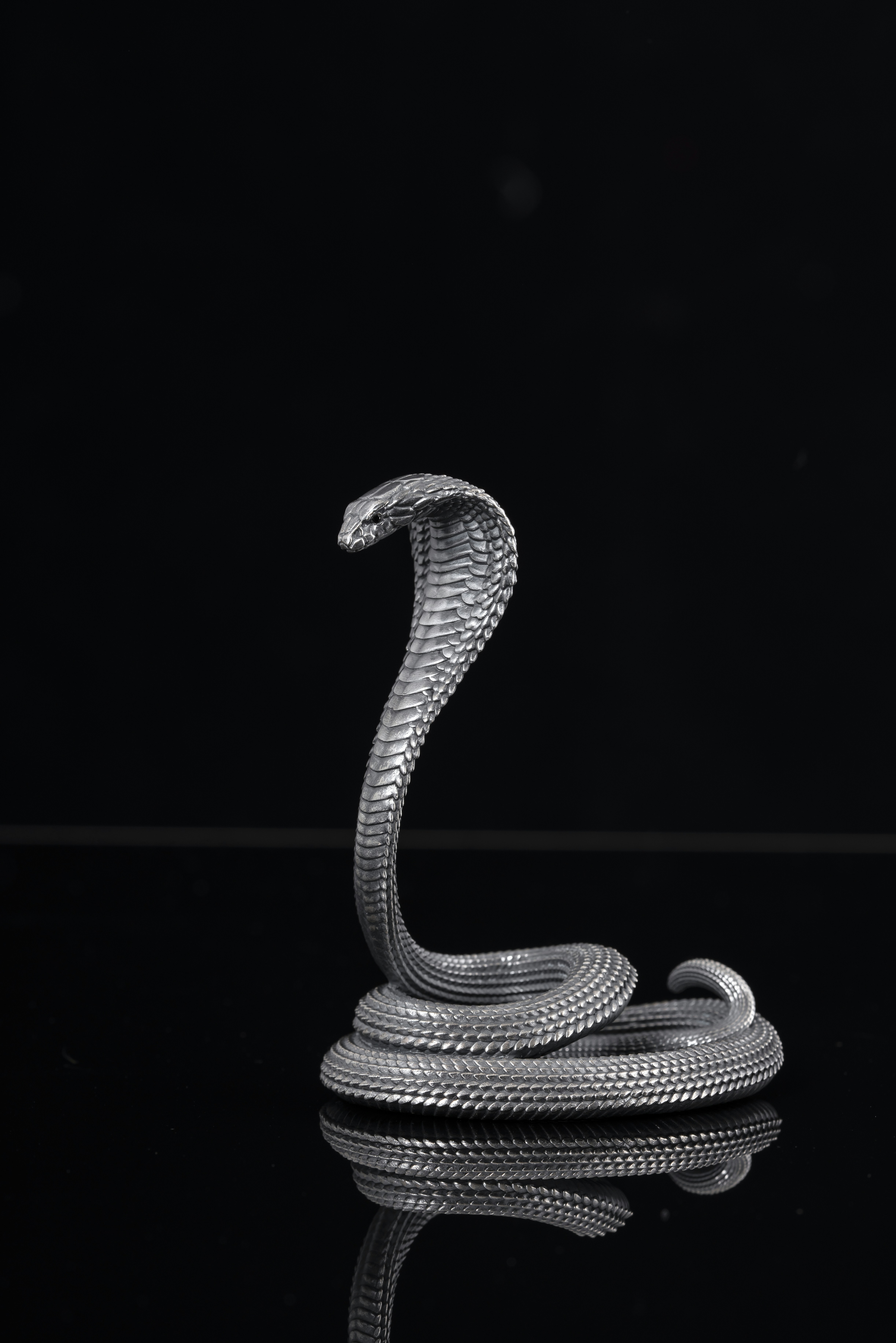 a silver snake sculpture sitting on top of a table