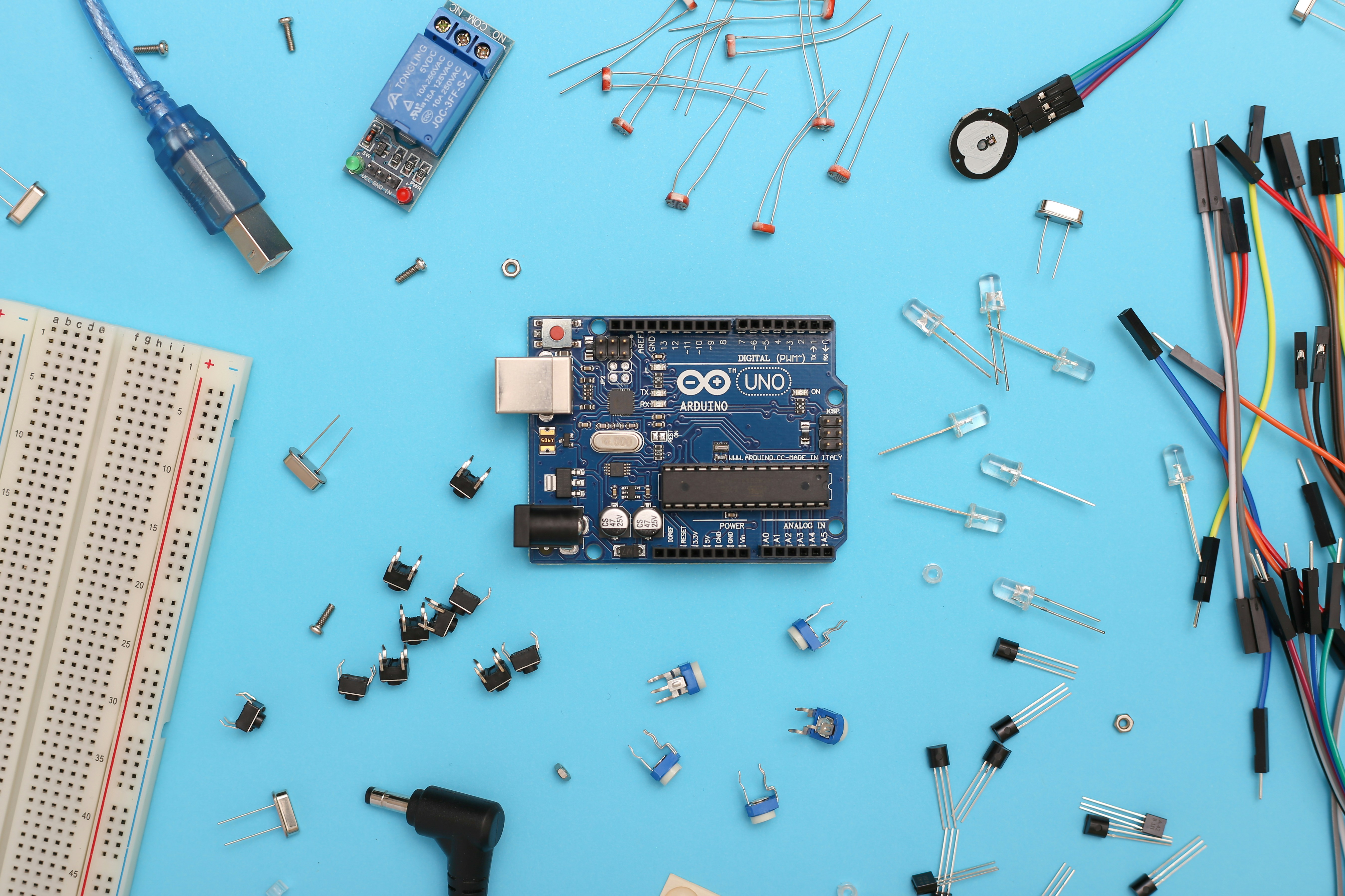 Arduino Uno and electronic parts on a blue surface. by Robotic Coding blue and black circuit board