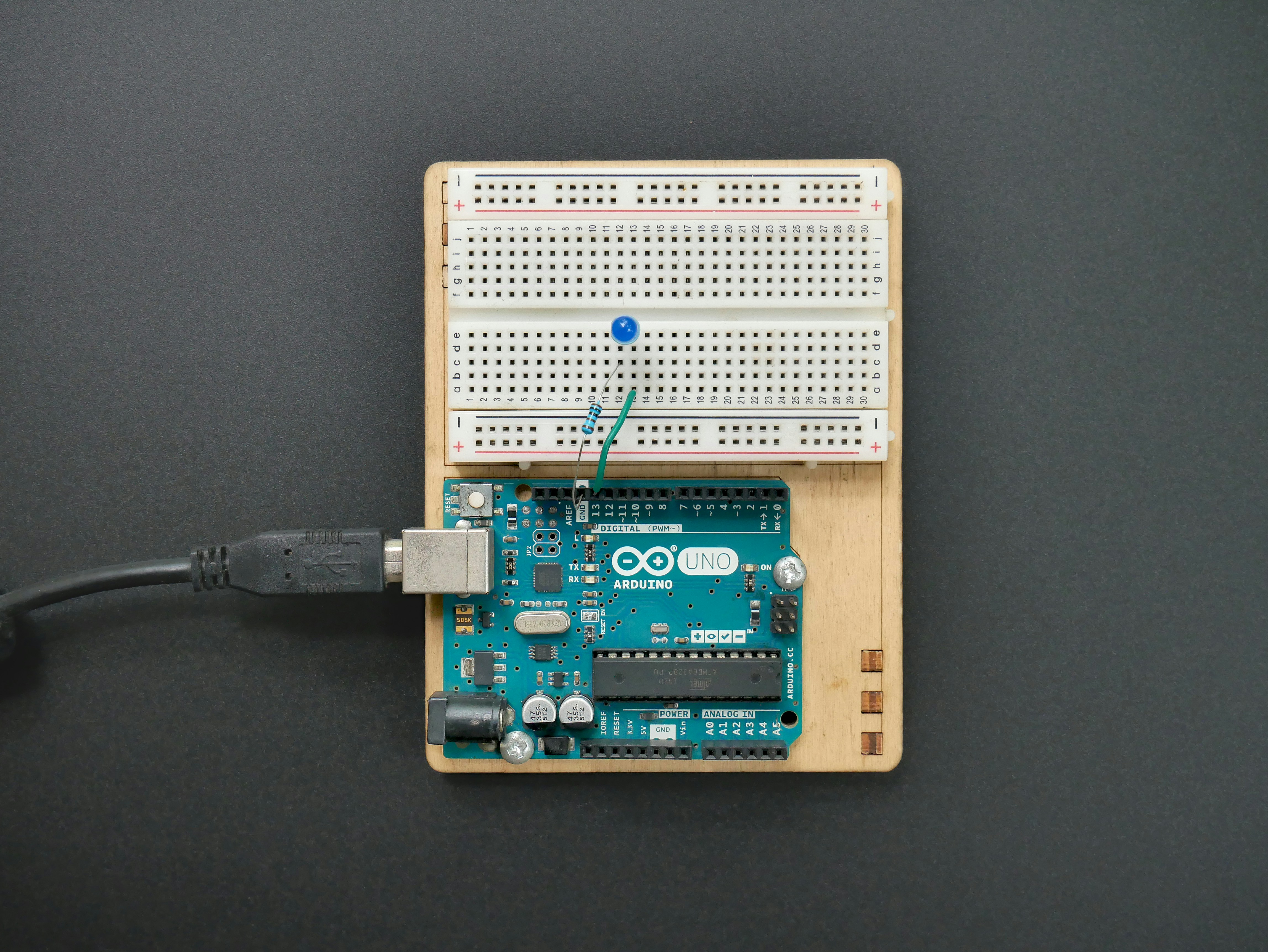 An Arduino Uno board with USB cable attached, along with a small breadboard with components on it. by Robotic Coding an electronic device with a micro board attached to it