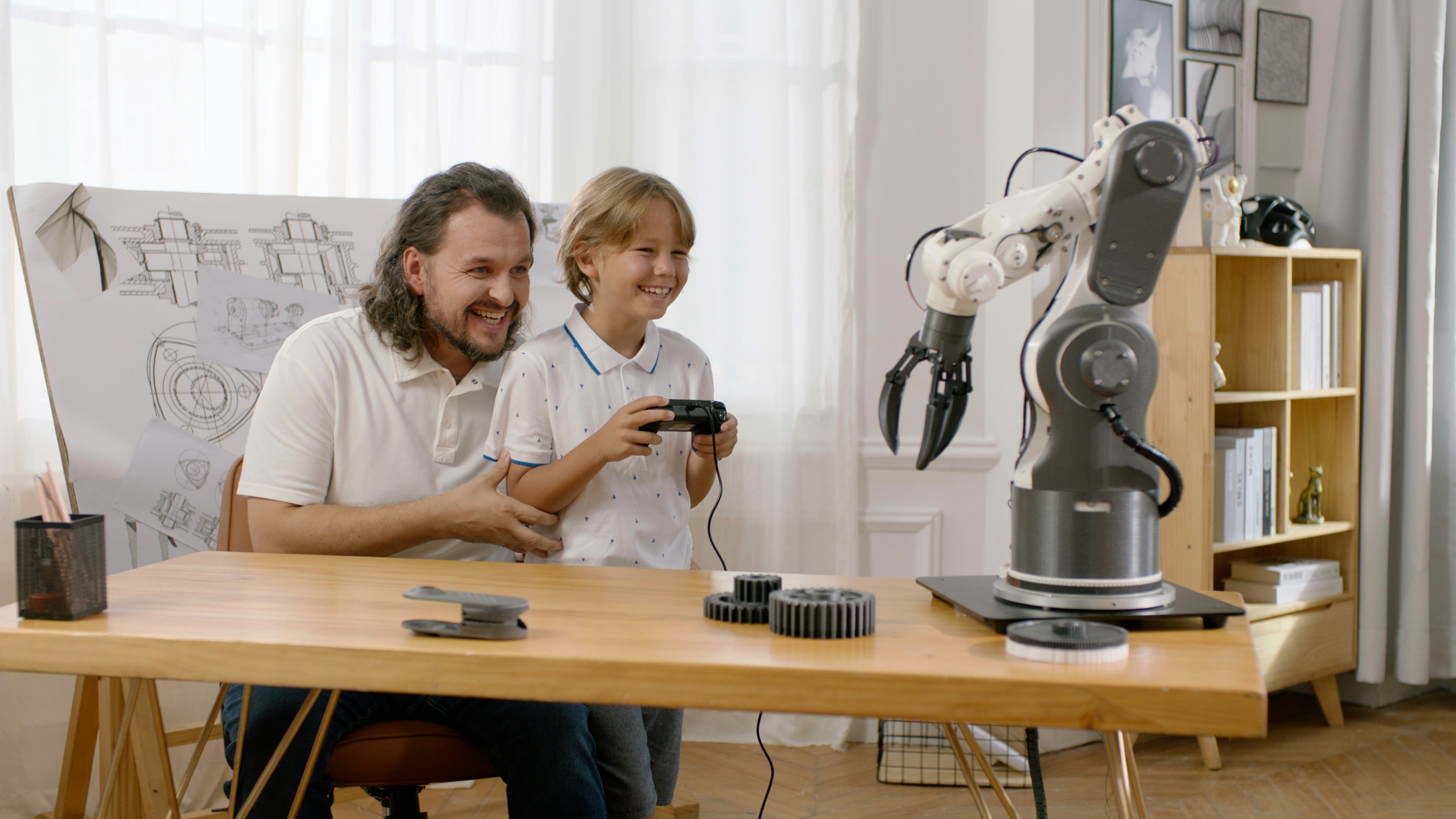 A father and son share a fun educational experience with a robotic arm made with Snapmaker 3d printer. by Robotic Coding A man and a child are sitting at a table