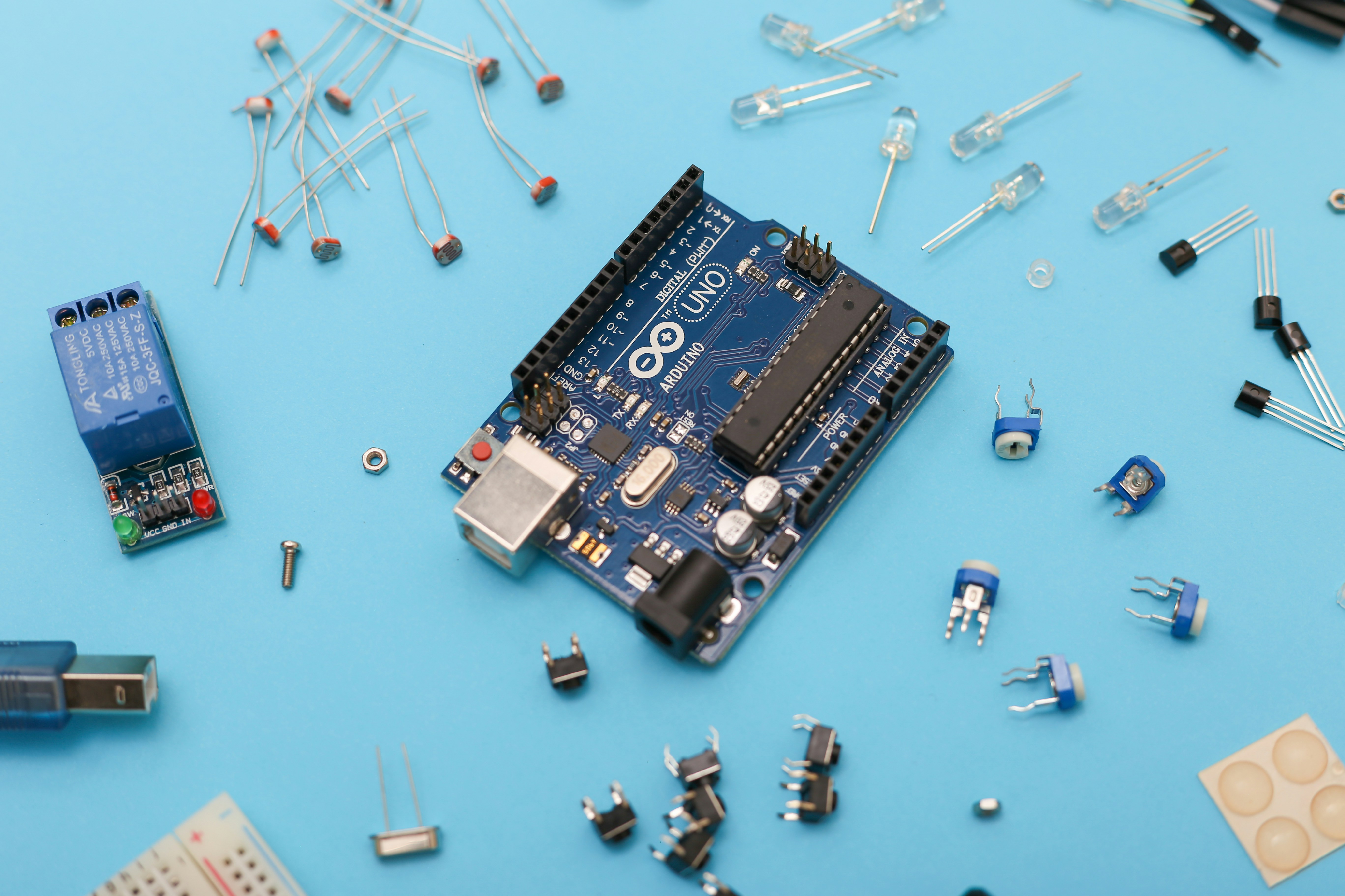 Arduino Uno and electronic parts on a blue surface. by Robotic Coding blue and black circuit board