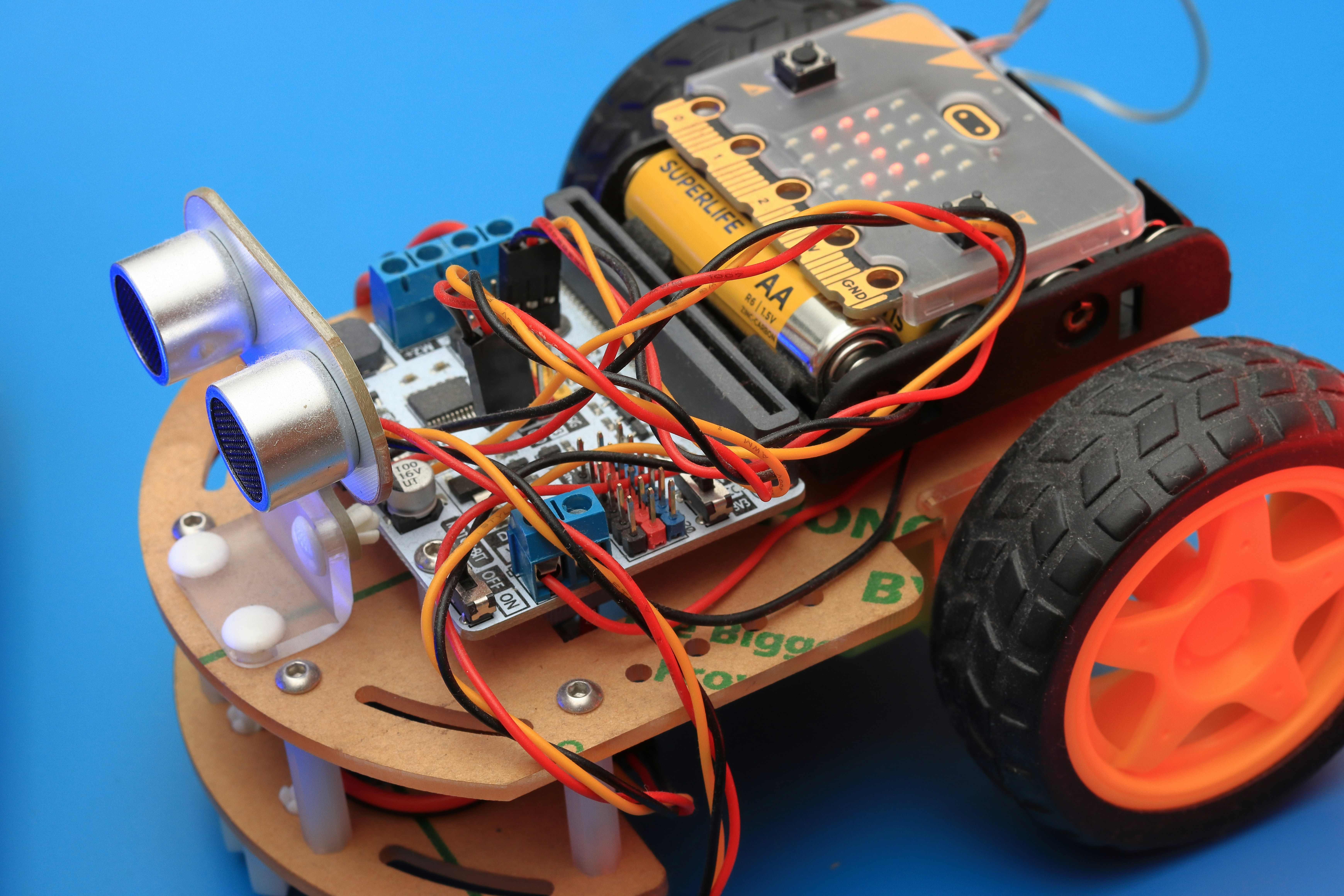 Playing with robot toy at school robotics class. by Robotic Coding a small robot car with wheels and wires attached to it