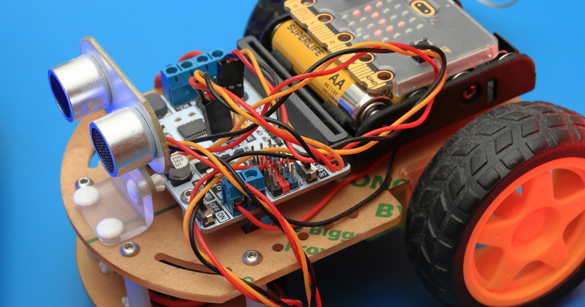 Playing with robot toy at school robotics class. by Robotic Coding a small robot car with wheels and wires attached to it