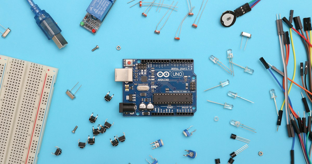 Arduino Uno and electronic parts on a blue surface. by Robotic Coding blue and black circuit board
